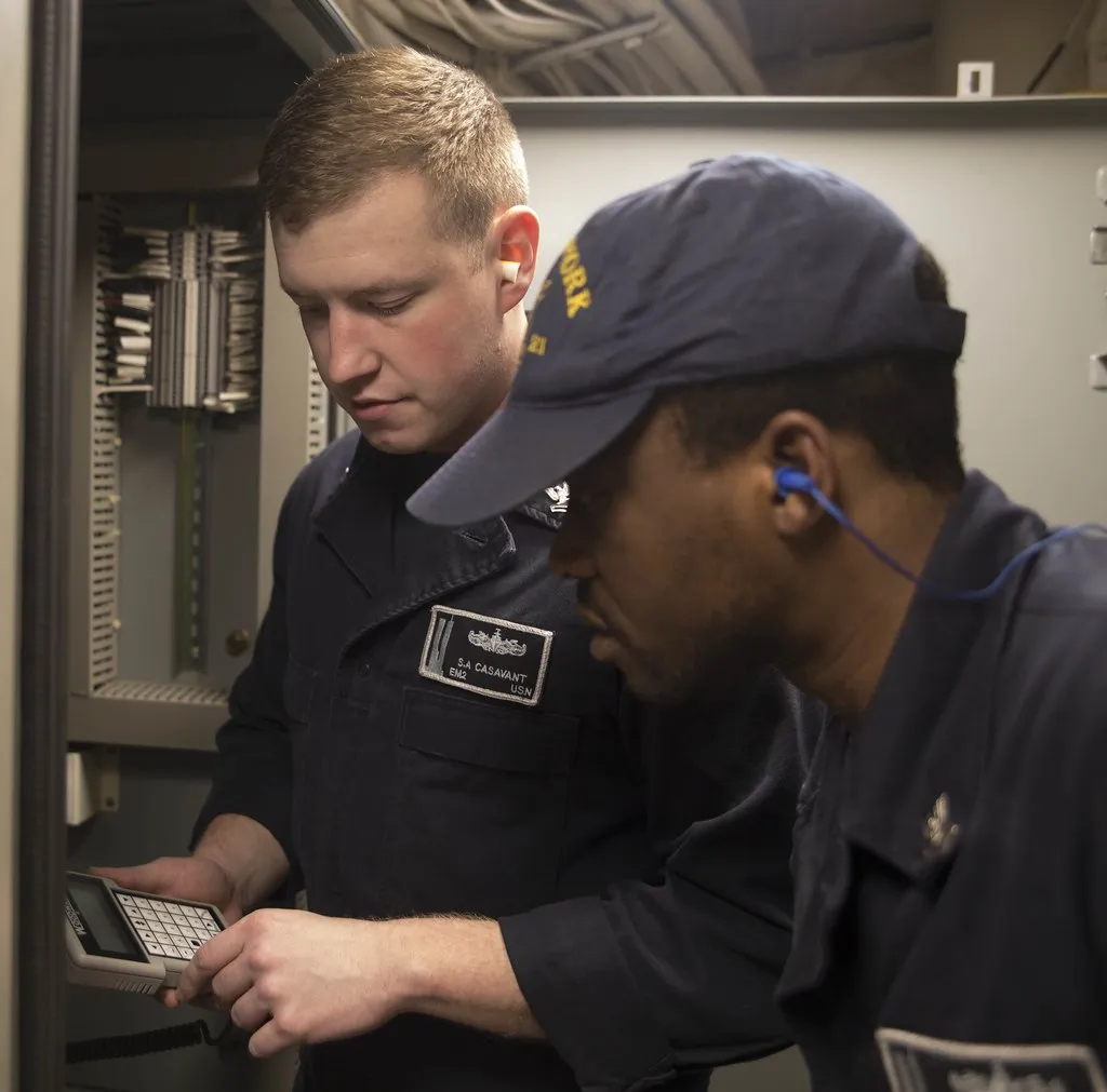 Technician servicing an open electrical control panel during building automation maintenance